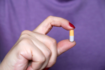 Pill in female hand close-up, woman holding capsule. Concept of medication intake, pharmacy, health care, pharmacist or scientist