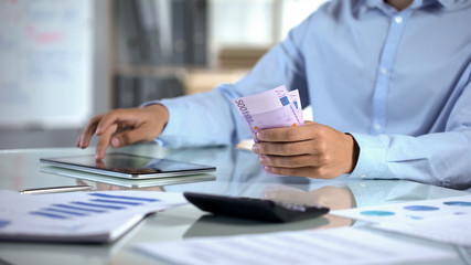 Businessman counting euro and planning company budget by tablet application