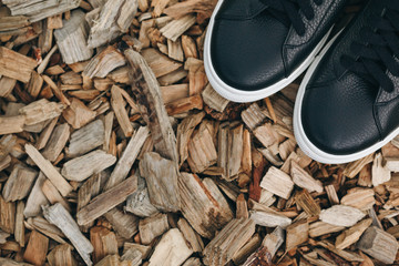 Black leather sneakers on sawdust. Copy space