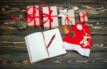 Christmas gifts with a decoration on a wooden board and a notebook with a pen for records