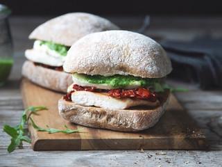 Sandwiches with grilled chicken, dried tomatoes, mozarella and pesto sauce.