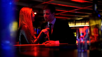 Fototapeta na wymiar Man listening attentively to his woman while they talking in night club on bar