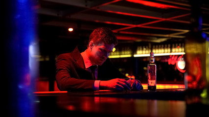 Stressed tired business man drinking in bar after hard work day, overworking