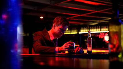 Obraz na płótnie Canvas Lonely depressed man drinking whiskey in nightclub, thinking over problems