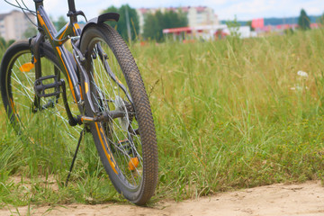 Fototapeta na wymiar A black bicycle in the panoramic view of green field.