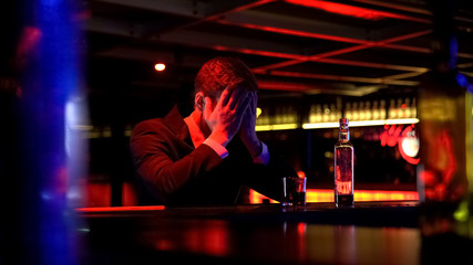 Businessman drinking whiskey in bar, rubbing head in desperate, bankruptcy