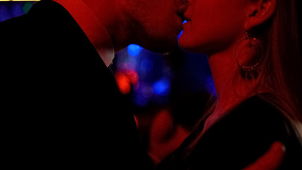 Male and female passionately kissing at night club, carefree nightlife, close-up