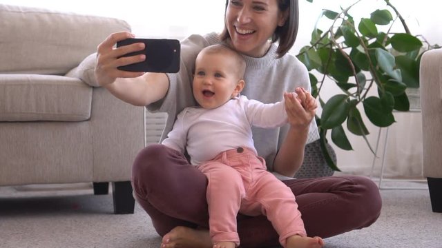 Mother taking selfie with baby daughter using mobile phone