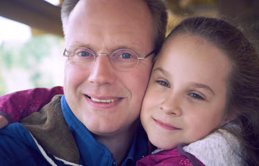 Mature father embraced by his daughter, smiling and laughing together at the terrace cafe. Happy family moments, father and daughter relationship concept