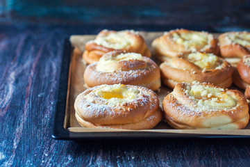 Homemade buns with ricotta and jam on a baking sheet.