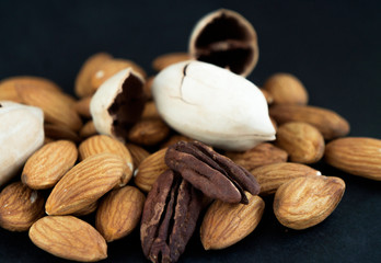 Almond and pecan nuts on black surface