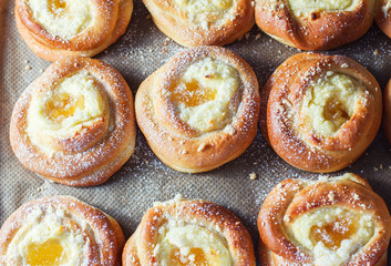 Homemade buns with ricotta and jam on a baking sheet.