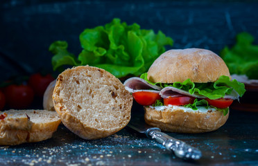 Homemade sandwich with ham and vegetables on wooden background