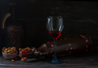 Ceramic jug for wine , cheese, nuts on a wooden board, background.