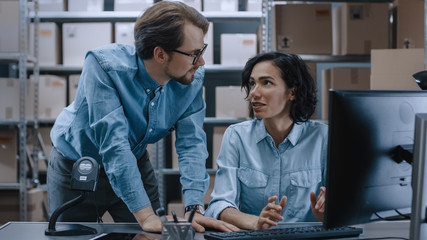 Male and Female Warehouse Inventory Managers Talking, Solving Problems, Using Personal Computer and...