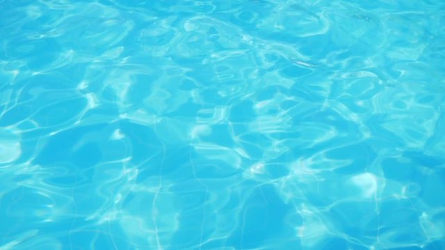 Ripple on blue water in the pool with light reflections.