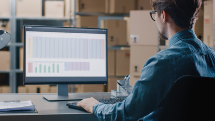 Warehouse Inventory Manager Works with a Spreadsheet on a Personal Computer while Sitting at His...
