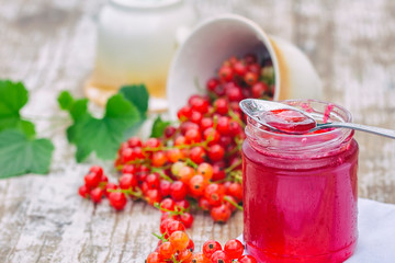Red currants and jar of jam in garden. Natural light.
