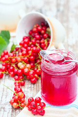 Red currants and jar of jam in garden. Natural light.