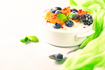 Healthy food, snacks or breakfast. Homemade Greek yogurt with blueberries, blackberries, persimmons and mint. On a concrete stone table.