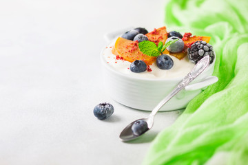 Healthy food, snacks or breakfast. Homemade Greek yogurt with blueberries, blackberries, persimmons and mint. On a concrete stone table.
