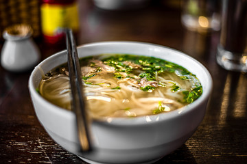 Pho Bo - Vietnamese fresh rice noodle soup with chicken, herbs and chili. Vietnam's national dish.