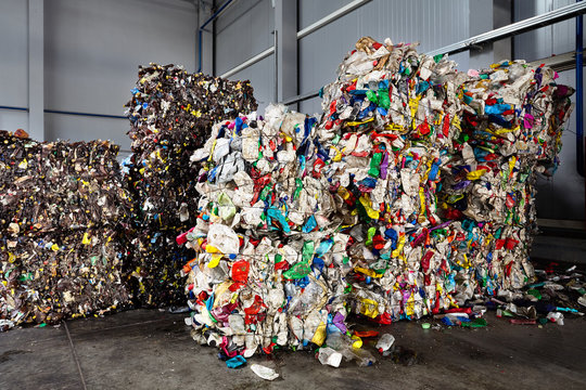 Compressed bales of polyethylene used bottles from drinks and detergents sorted and packaged for processing workshop at modern waste recycling plant