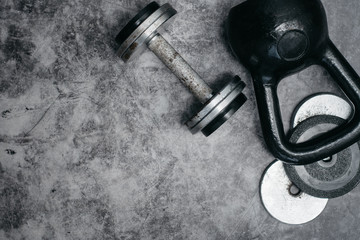 Fototapeta na wymiar Fitness or bodybuilding concept background. Old iron dumbbells and Kettlebell on grey, conrete floor in the gym. Top view. Healthz lifestyle.