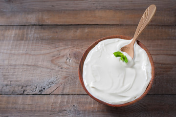 Greek yogurt in a wooden bowl on a rustic wooden table.