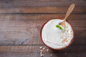 Greek yogurt in a wooden bowl on a rustic wooden table.