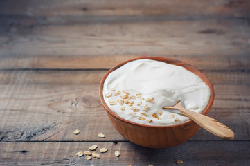 Greek yogurt in a wooden bowl on a rustic wooden table.