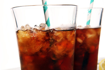 Softdrink with ice cubes, lemon and straw in glass