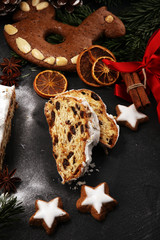 Traditional European Christmas pastry, fragrant home baked stollen, with spices and dried fruit. Sliced on rustic table with xmas tree branches and decorations