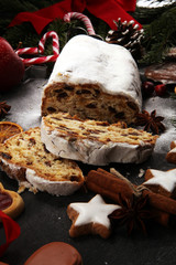 Traditional European Christmas pastry, fragrant home baked stollen, with spices and dried fruit. Sliced on rustic table with xmas tree branches and decorations