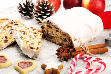 Traditional European Christmas pastry, fragrant home baked stollen, with spices and dried fruit. Sliced on rustic table with xmas tree branches and decorations