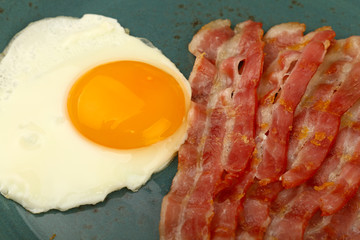 Close up sunny side egg and bacon on blue plate