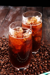 Ice coffee on a rustic table with cream being poured into it showing the texture and refreshing look of the drink