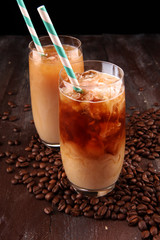 Ice coffee on a rustic table with cream being poured into it showing the texture and refreshing look of the drink