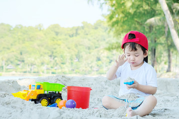 Closeup cute asian kid play with sand and toy on beach textured background