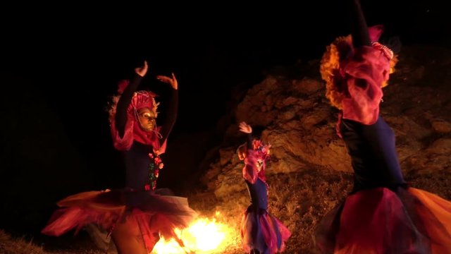 girls in a Venetian masquerade costume dancing in the open air. on the faces of people of the mask without emotion.