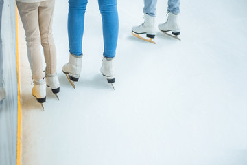 Obraz premium partial view of family in skates standing on ice rink