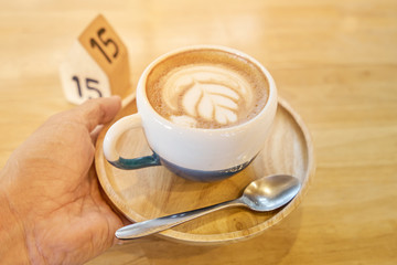 Mand's holding a coffee cup on wood table with natural light and copyspace