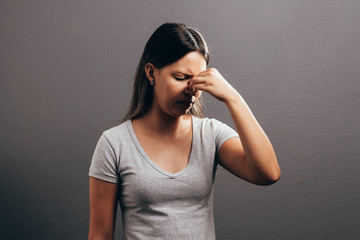 Sinus pain, sinus pressure, sinusitis. Sad woman holding her nose and head because sinus pain