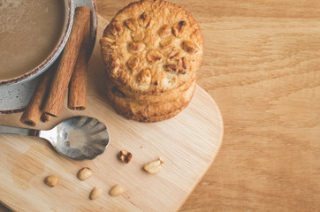 Fototapeta premium cinnamon sticks, cookies with nuts and a cup of coffee/breakfast with cinnamon sticks, cookies with nuts and a cup of coffee on a wooden tray. Top view and copy space