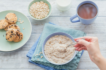 Oatmeal porridge bowl on the white wooden background.