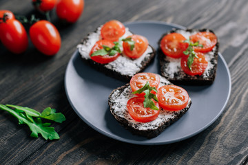 Appetizer with black bread, cream cheese and tomatoes