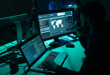 Wanted hackers coding virus ransomware using laptops and computers. Cyber attack, system breaking and malware concept.