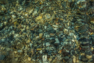 Fototapeta na wymiar abstract unfocused fuzzy colorful stones on sea bottom surface background through the water 