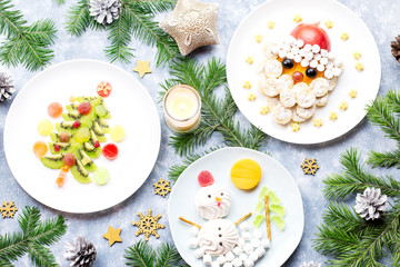 Obraz na płótnie Canvas Christmas food for children - kiwi Christmas tree, marshmallow snowman, banana Santa Claus. Top view