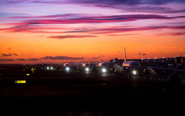 Airplane line up on runway waiting for take off in a beautiful sunset
